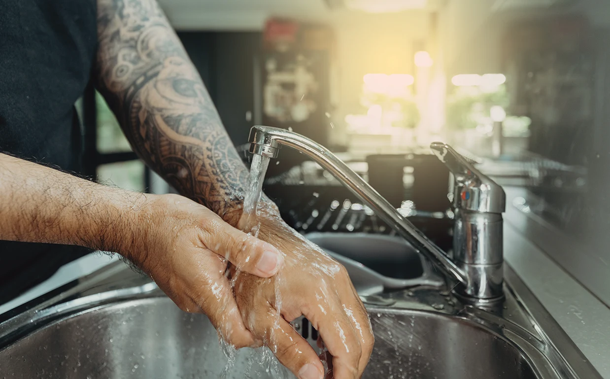 A man with tattoos washing his hands